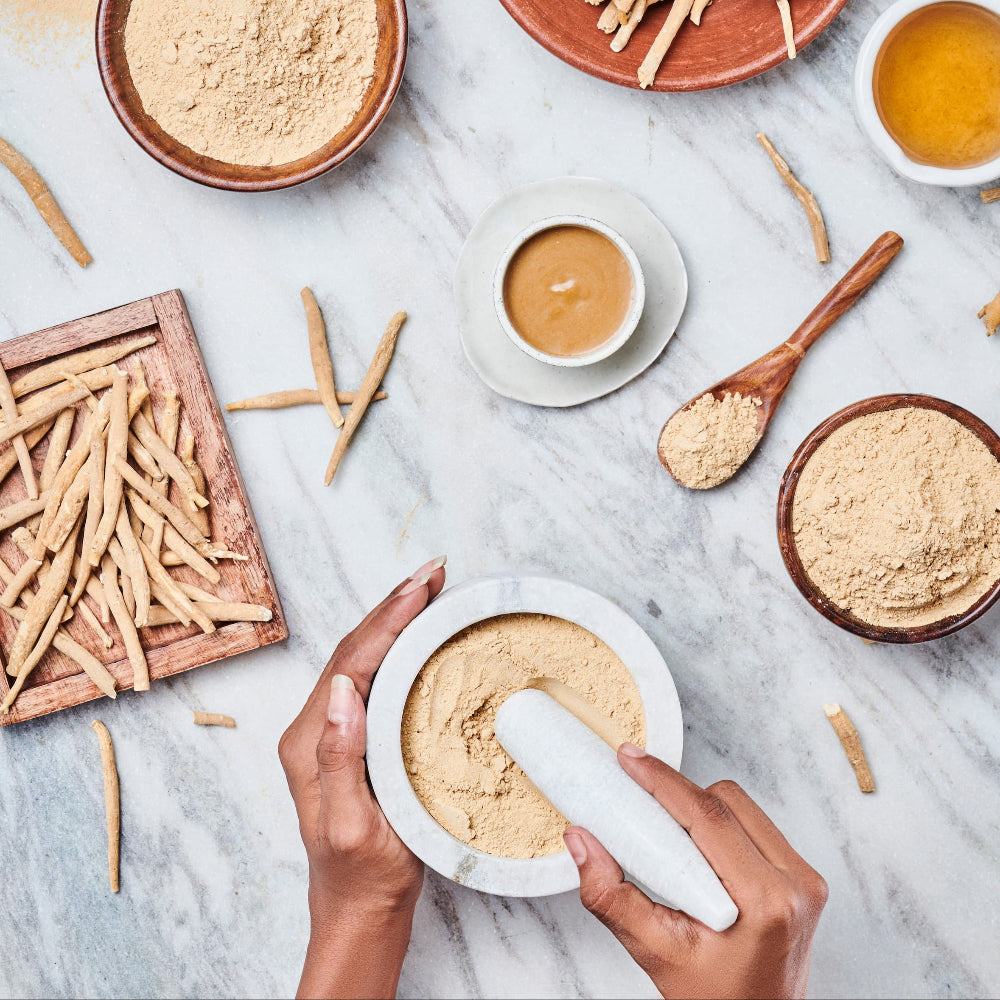 Hands using a mortar and pestle with KSM-66 Ashwagandha on a marble surface